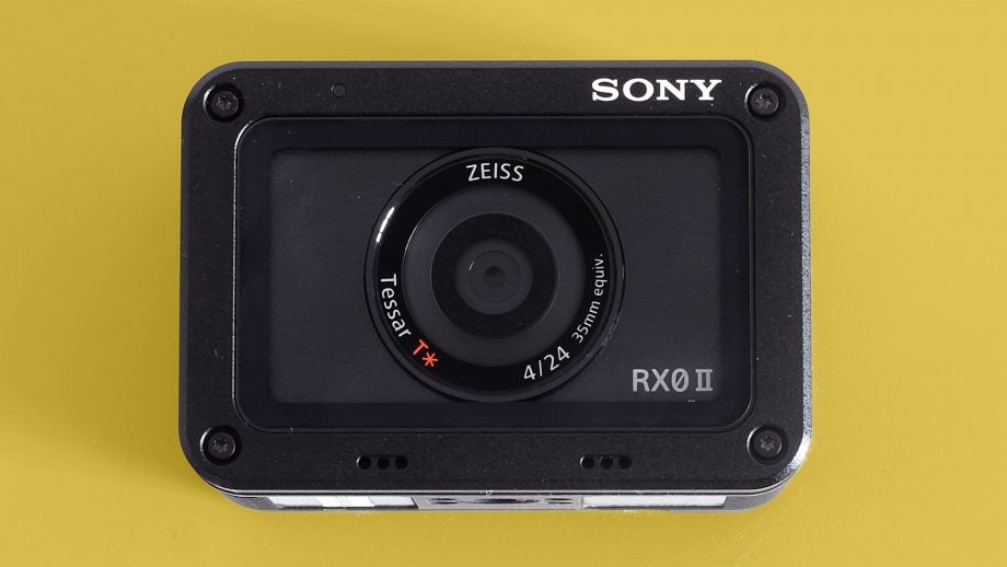 Front panel view from top of a black Sony RX0 II kept on a yellow background