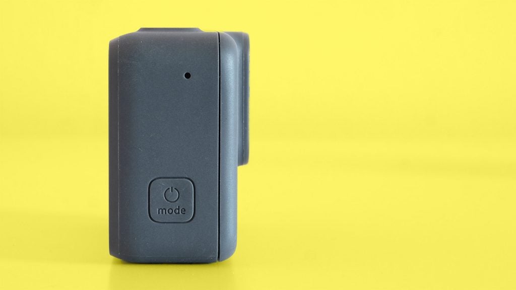 Side view of a black GoPro Hero7 silver camera standing on yellow background
