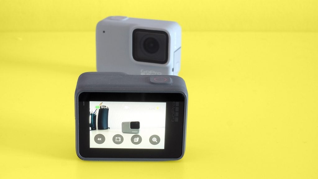 Back screen panel view of a black GoPro Hero7 silver camera standing on a yellow background
