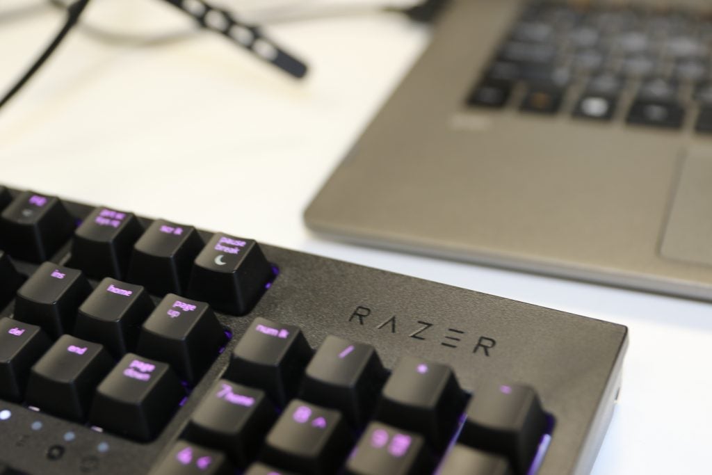 Close up view of Razer logo on a black Razer keyboard kept on a white table