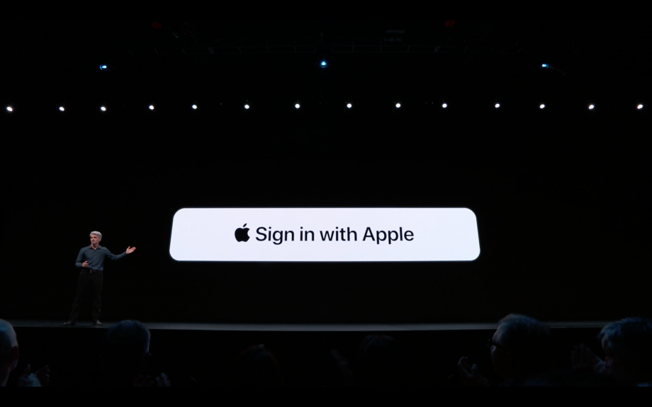 A man standing on a stage with Sign in withb Apple option displayed on the screen behind
