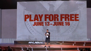 A man standing on stage with The Division 2 free to play displayed on the screen behind