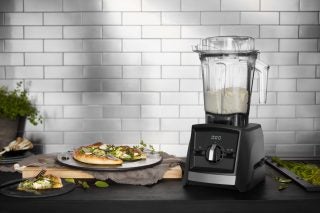A Vitamix A2300i belnder with it's empty jar fixed on top kept on a table with food kept around