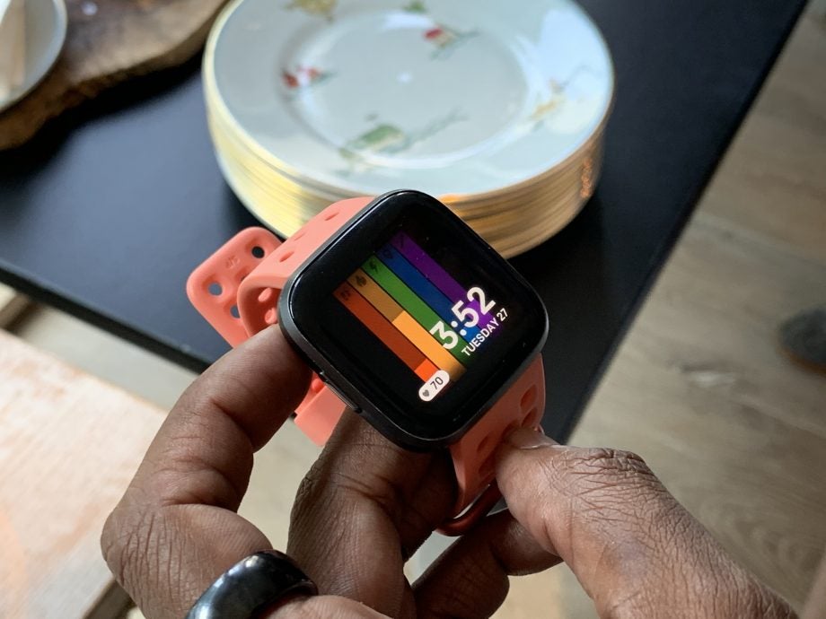 A Fitbit Versa 2 wore on hand displaying date and time with other details