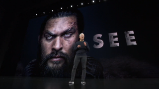Tim Cook standing on stage with SEE on Apple TV Plus displayed on screen behind