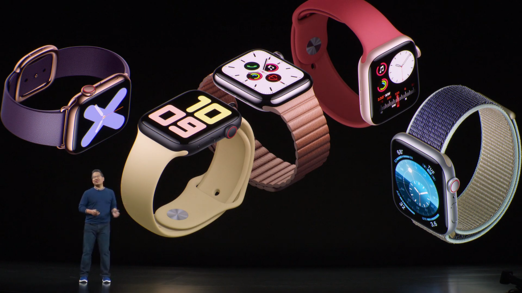 A man standing on stage with different Apple Watch series 5 displayed on the screen behind