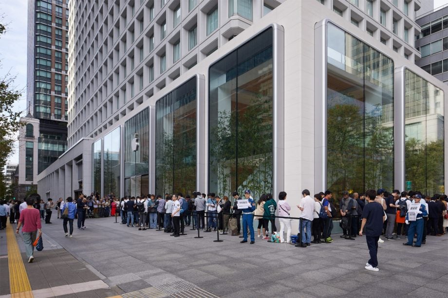 A street with a long queue outside and Applle store for Apple iPhone 11