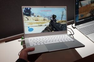A Razer Blade Stealth Ice Lake held in hand displaying an ongoing game