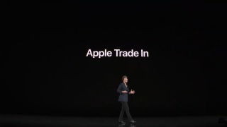 A woman standing on stage with Apple trade in displayed on screen behind