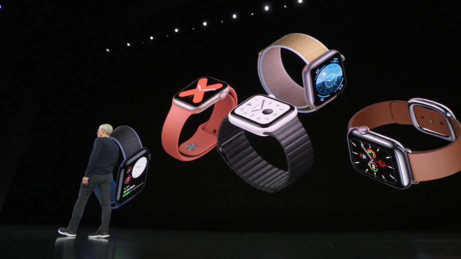 Tim Cook standing on stage with Apple watches displayed on screen behind