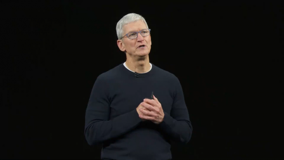 Tim Cook wearing glasses standing on stage on a black background