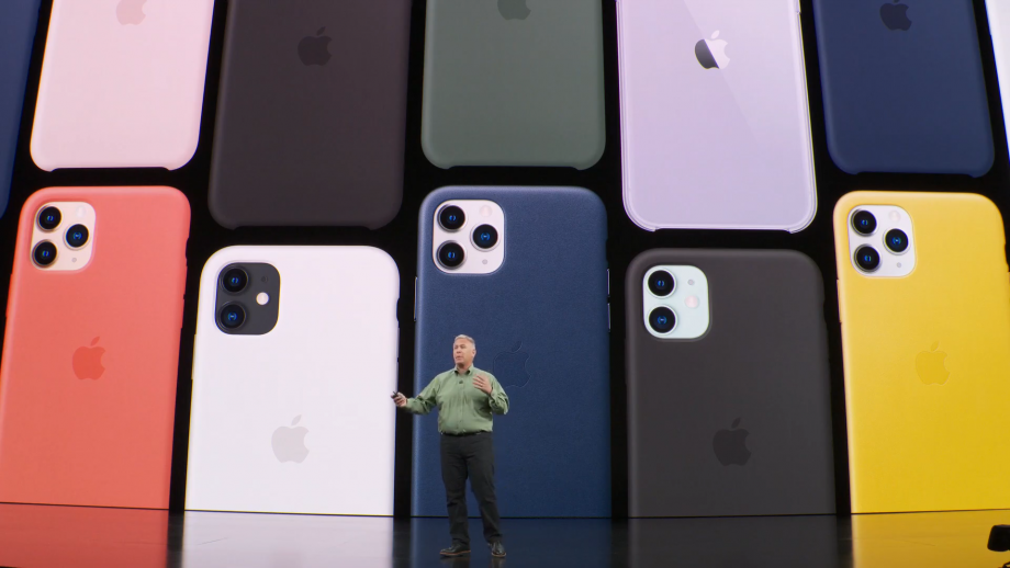 An old man standing on stage with an iPhone 11 color variants displayed on screen behind