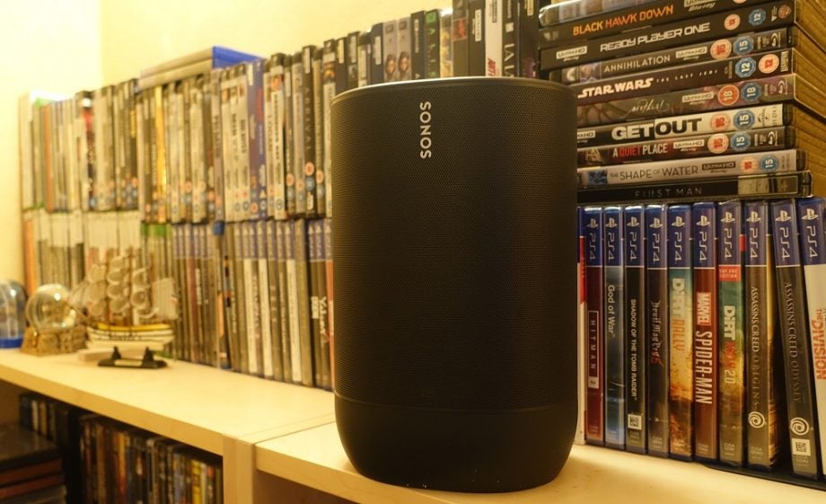 Right angled view of a black Sonos Move speaker standing on a shelf in front of PS game's cassettes