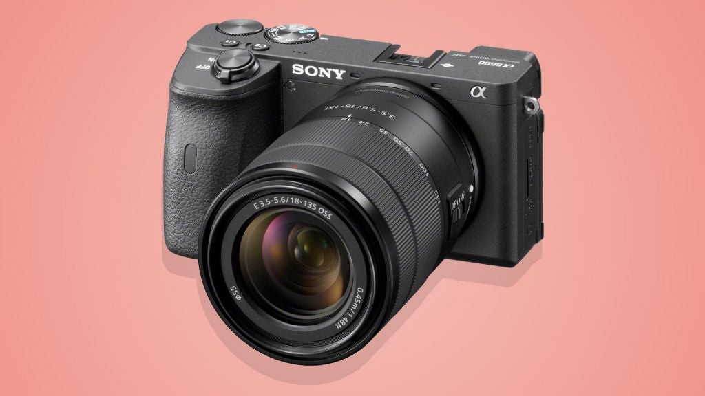 Right angled view of a black Sony Alpha 6600 camera standing on a pink background