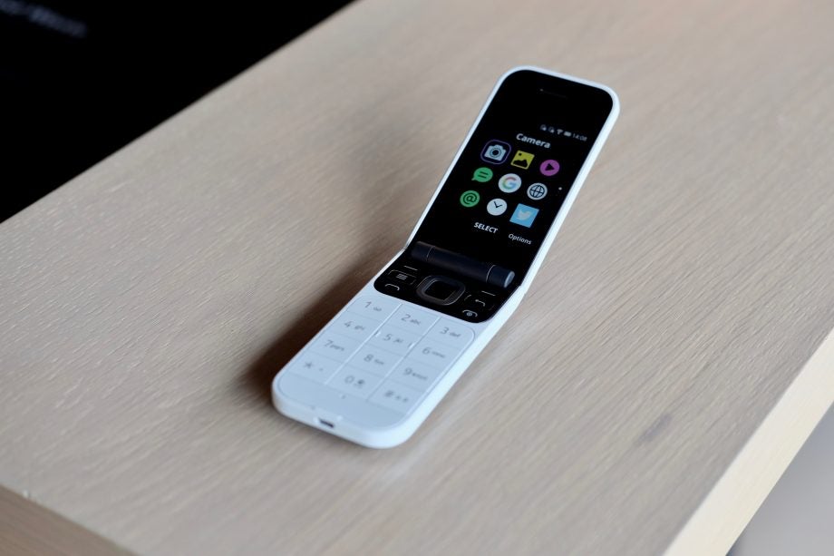 A white Nokia 2720 flip phone kept on a table displaying menu screen