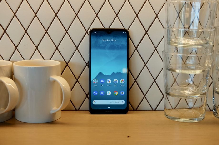 A black Nokia 6.2 smartphone standing against a wall displaying homescreen