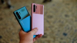 Two different colored Huawei P30 Pro held in hand facing back, back panel view