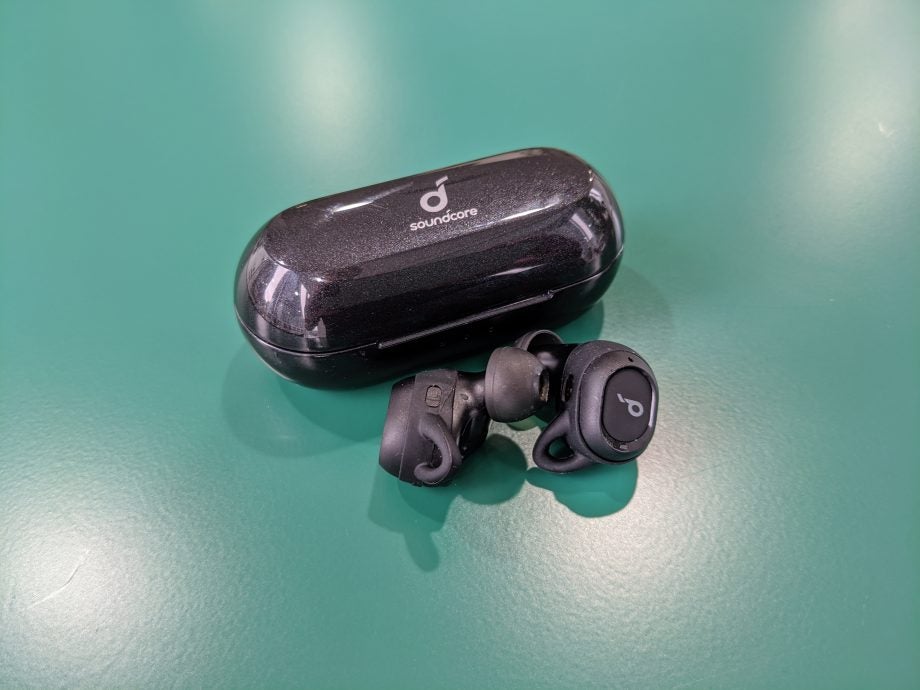 Black Anker Soundcore Liberty Neo earbuds with it's case kept behind on a table