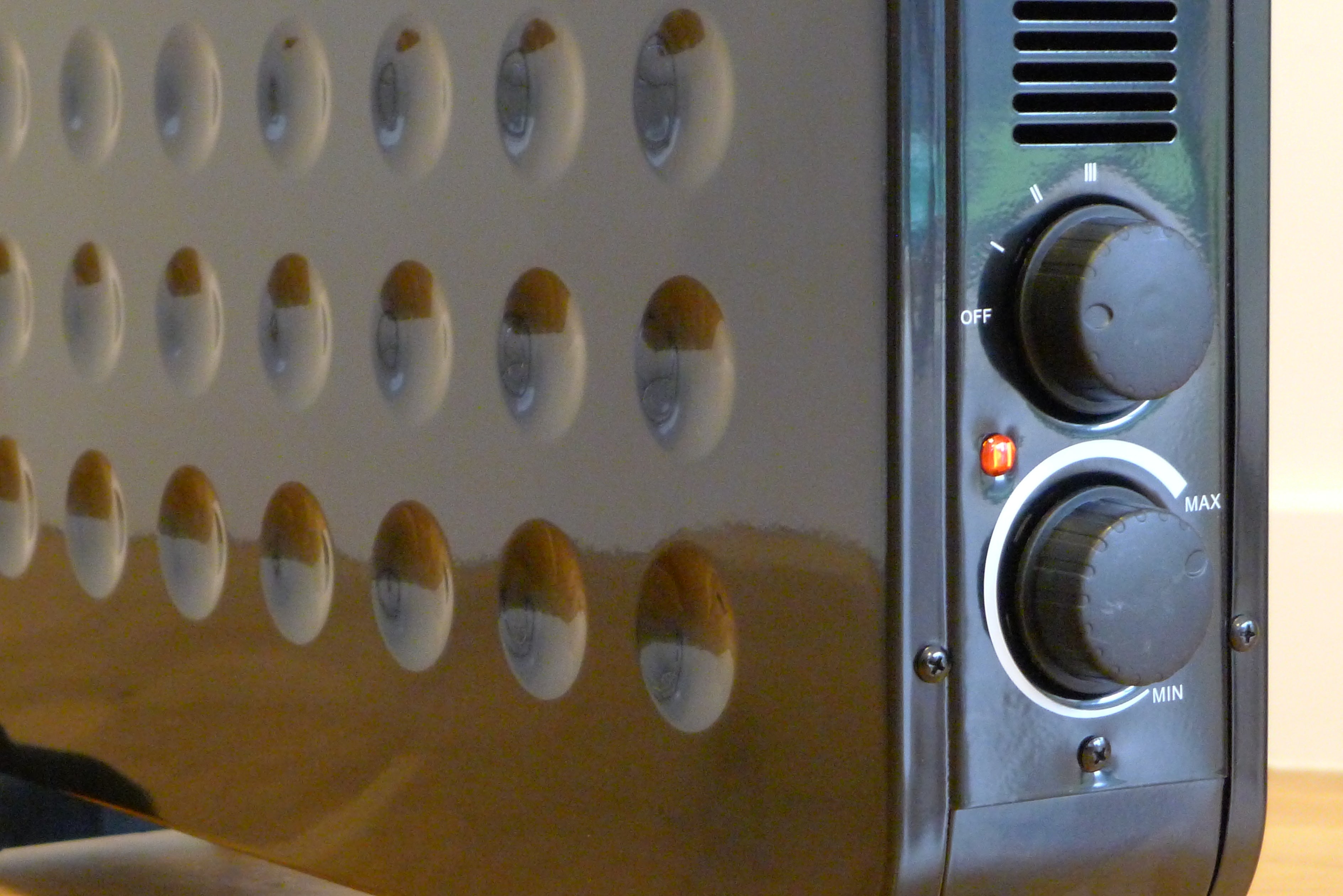 Left angled view of rotating knobs on front panel of a black Fine Element contemporary convector heater