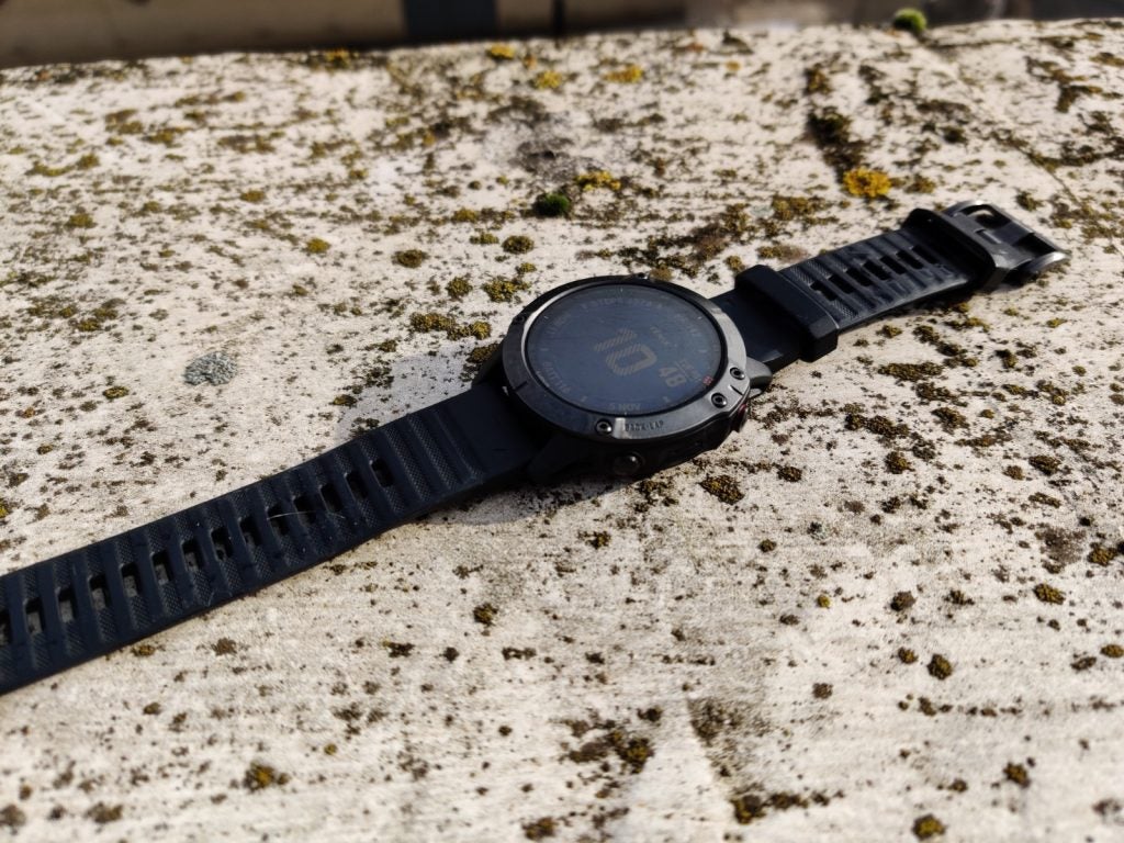 A black Garmin Fenix 6 watch kept on a concrete floor