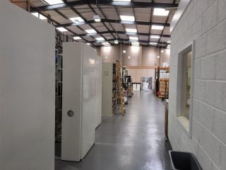 A small path in a warehouse with boxes standing on left and a room on right