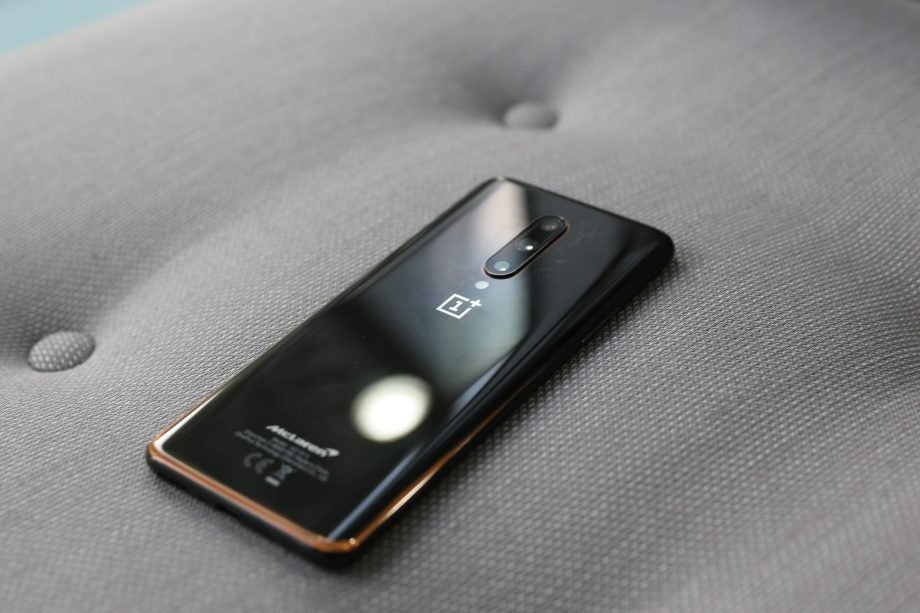 Back panel view of a black One Plus smartphone kept facing down on a couch