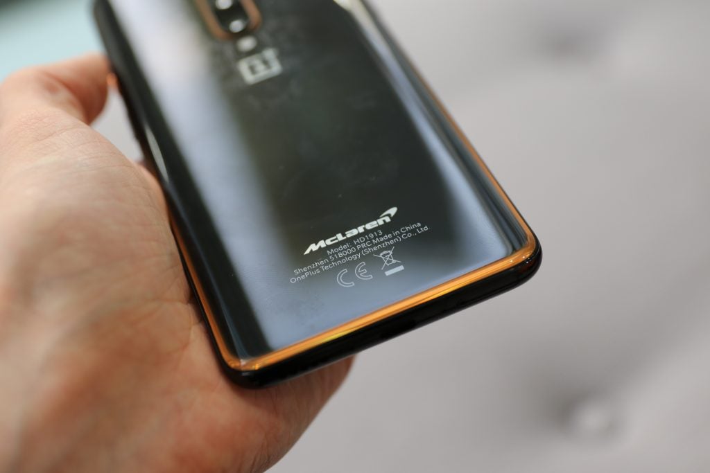 Bottom half back panel view of a black One Plus smartphone held in hand facing back