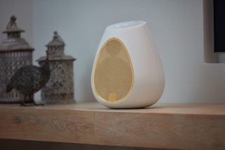 A white-yellow Linn series 3 speaker standing on a wooden shelf