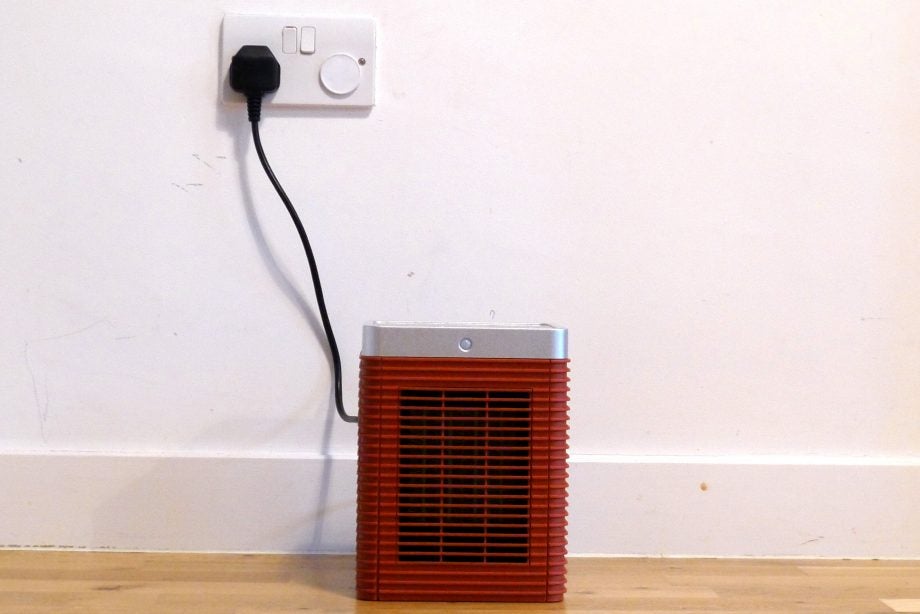 A brown-silver Meaco Heat Motion Eye heater plugged in standing on floor