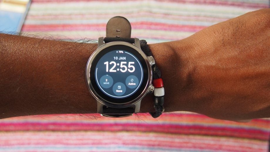 A silver-black Motorola smartwatch wore on hand displaying date and time