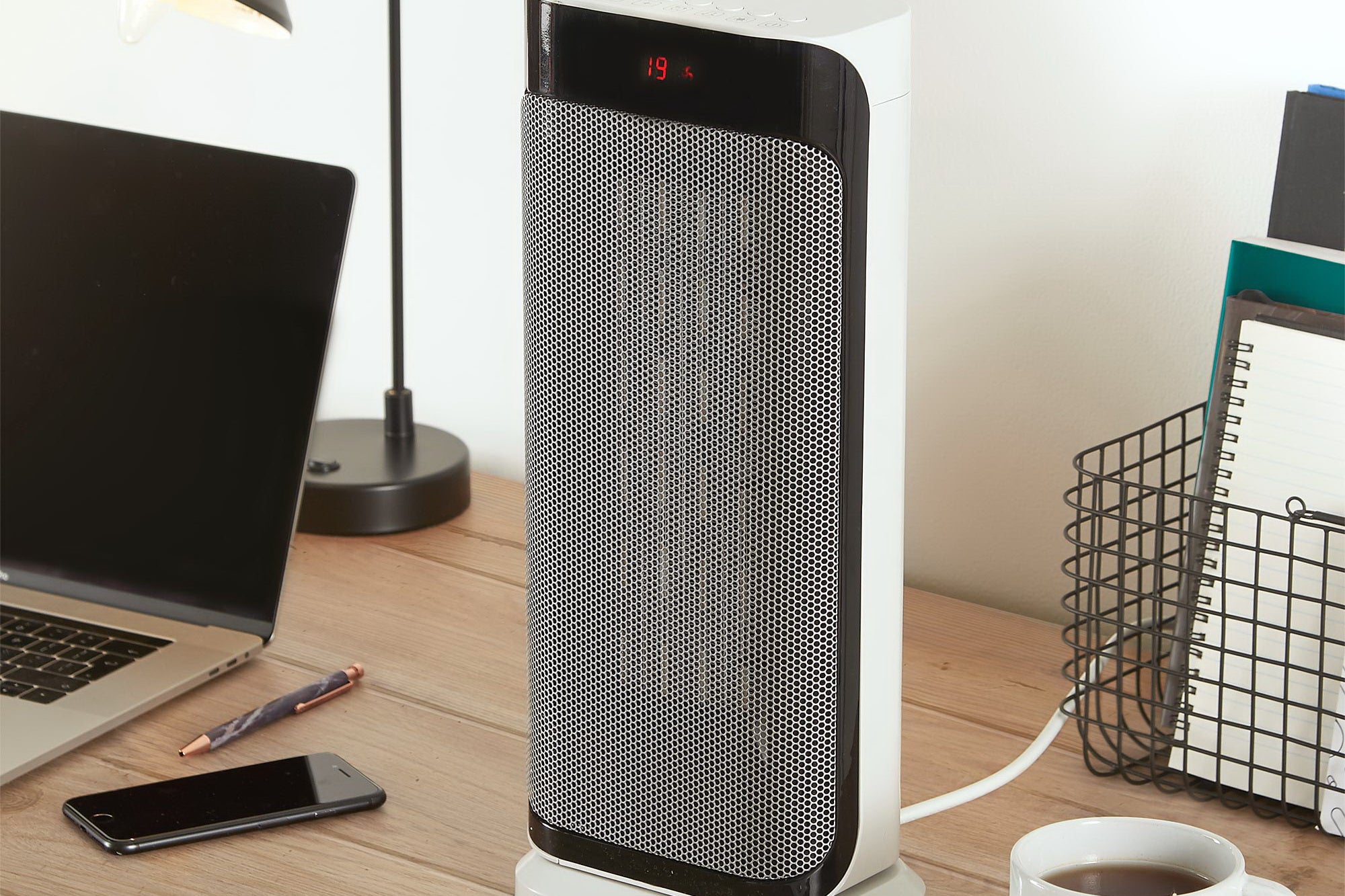 A gray-black and white VonHaus fan heater standing on a table beside a laptop