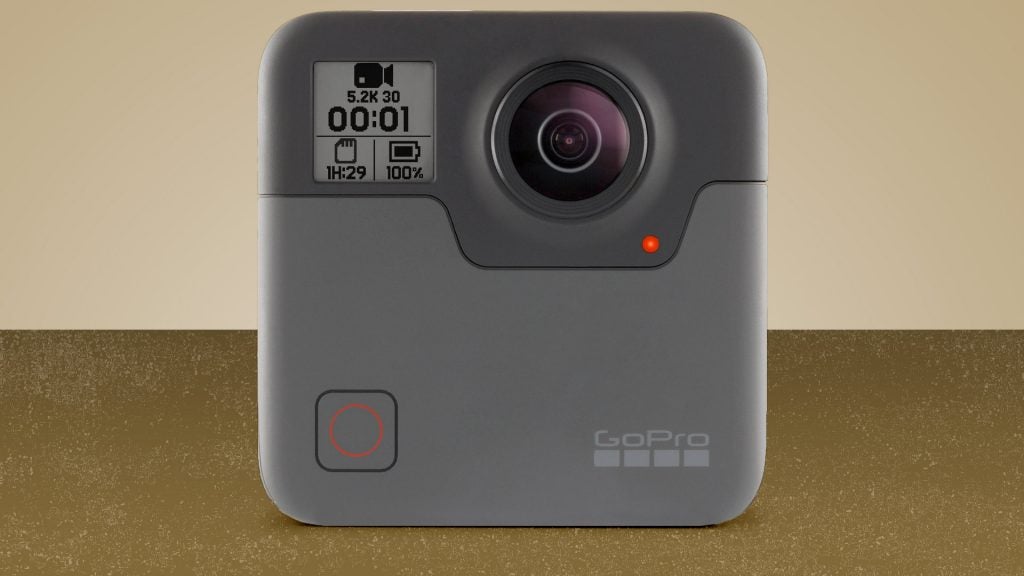 A gray GoPro Fusion camera standing on a brown-golden background