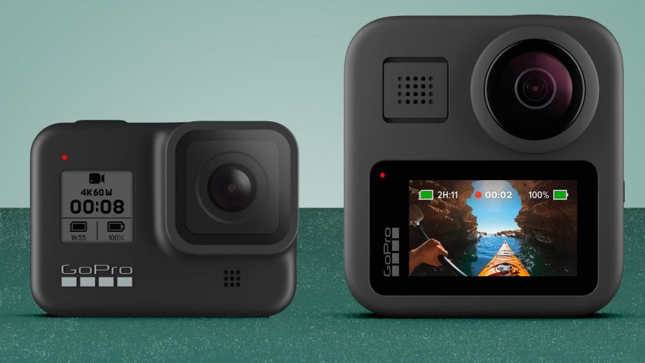 A black GoPro Hero 8 and a gray GoPro Max standing on a green background