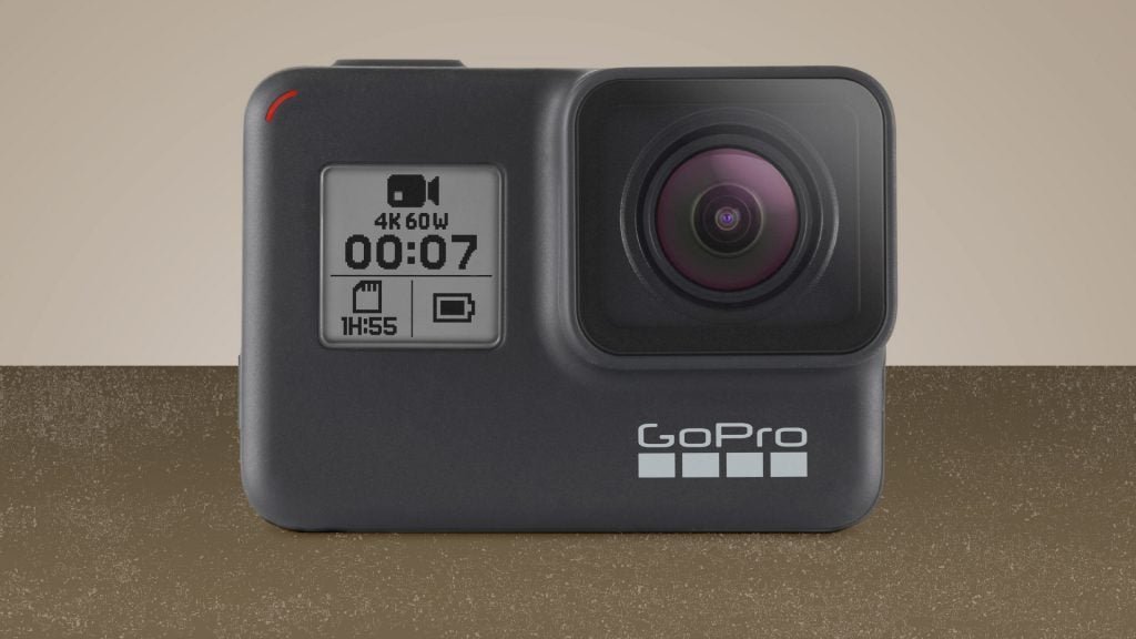 A black GoPro Hero 8 camera standing on a brown background