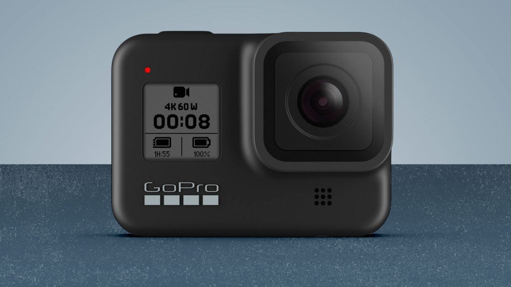 A black GoPro Hero 8 camera standing on a blue background