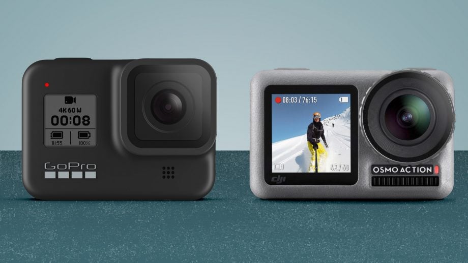 A black GoPro Hero 8 and a silver Osmo Action camera standing on a green background