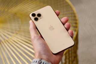 Back panel view of a cream colored iPhone 11 Pro held in hand facing down
