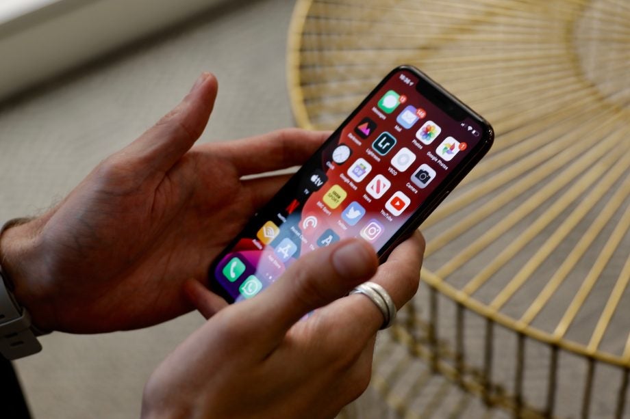 Side view of an iPhone 11 Pro held in hand displaying homescreen