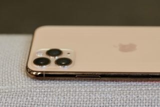 Top half side view of a cream colored iPhone 11 Pro laid facing down on a couch