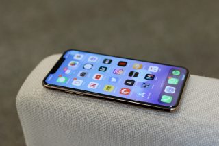 Left side edge view of an iPhone 11 Pro Max kept on a couch's back wall displaying homescreen