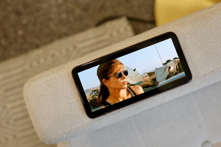 View from top of an iPhone 11 Pro Max kept on a couch's back wall displaying a scene from a movie