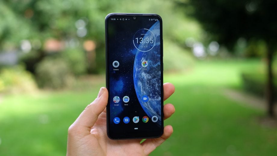 A Moto E6 held in hand displaying homescreen