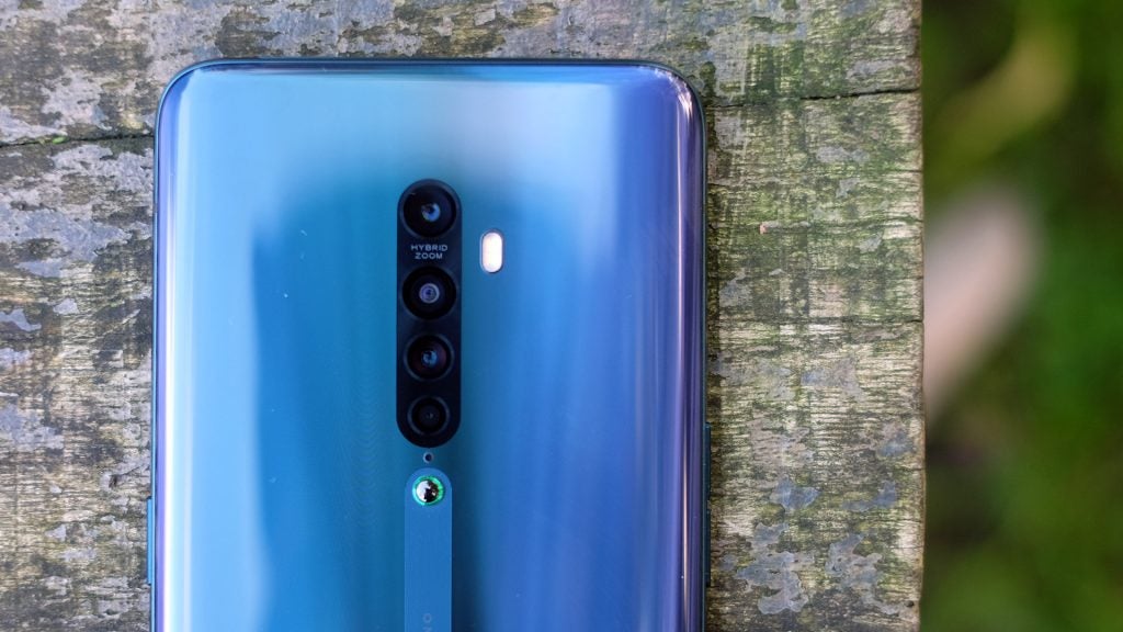 Top half back panel view a blue Oppo Reno 2 kept facing down on a wooden surfaceAn Oppo Reno 2 held in hand displaying homescreen