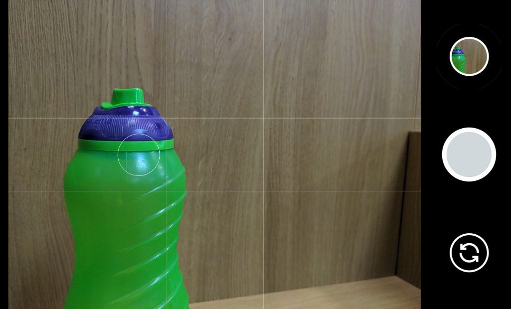 Screenshot of camera app displaying picture of a bottle kept on a wooden background