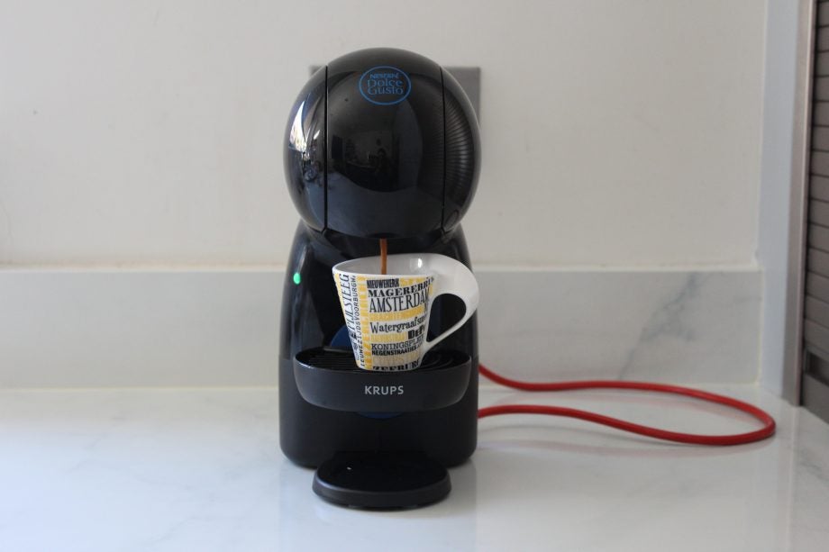 A coffee mug being filled from Nescafe Dolce Gusto Piccolo XS standing on a table