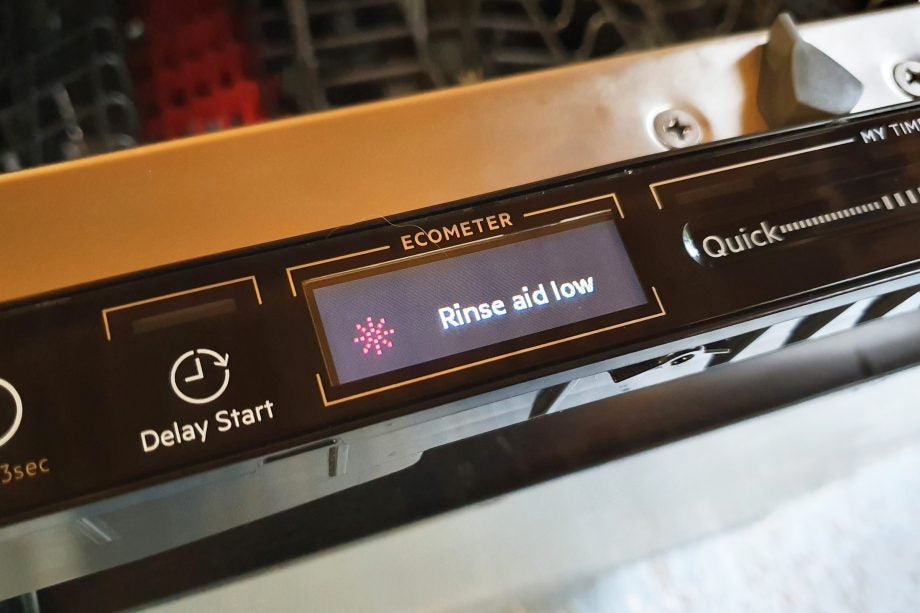 Close up view of tiny Ecometer on AEG dishwasher displaying Rinse Aid low mode