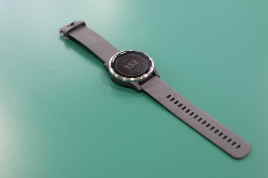 A black Garmin Vivoactive watch kept in a green table displaying date and time