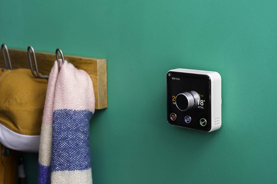 A black and white Hive Thermostat mounted on a green wall