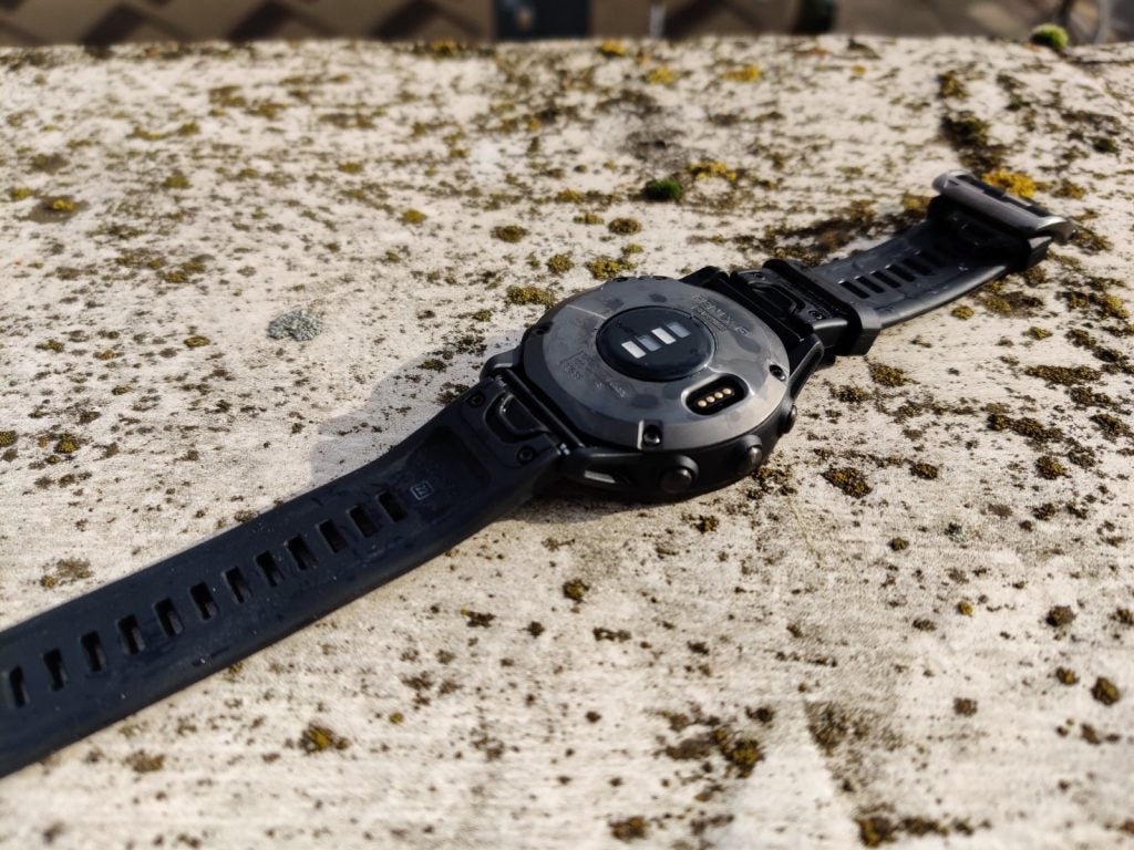 Back panel view of a black Garmin Fenix 6 watch kept on a concrete floor