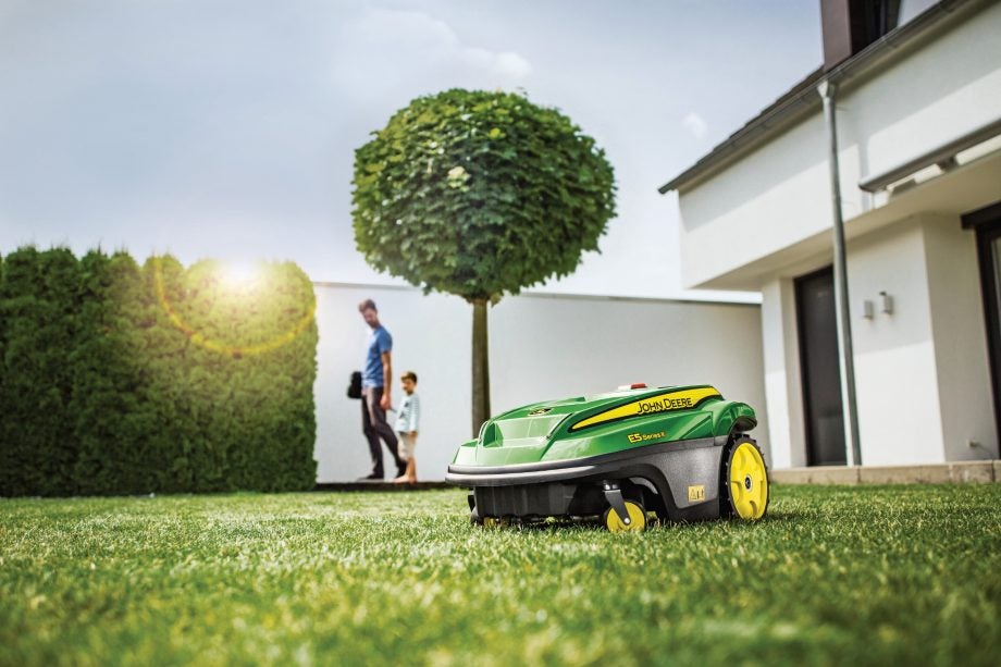 A green, yellow and black colored John Deere Tango robot lawnmower working in a lawn